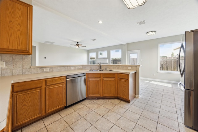 kitchen featuring ceiling fan, sink, kitchen peninsula, light tile patterned flooring, and appliances with stainless steel finishes