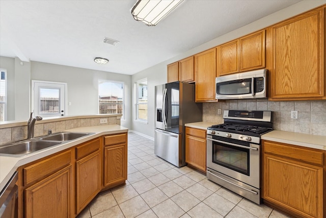 kitchen featuring decorative backsplash, sink, light tile patterned flooring, and appliances with stainless steel finishes