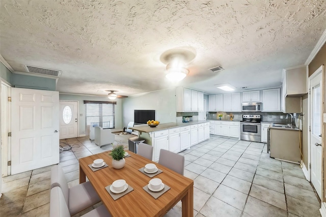 tiled dining space with ornamental molding, sink, a textured ceiling, and ceiling fan