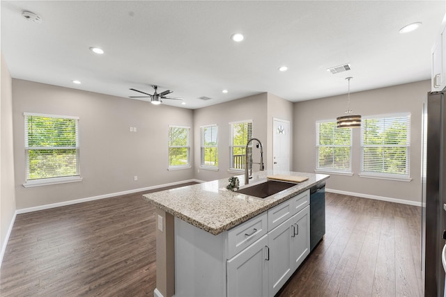 kitchen featuring pendant lighting, sink, white cabinets, and an island with sink