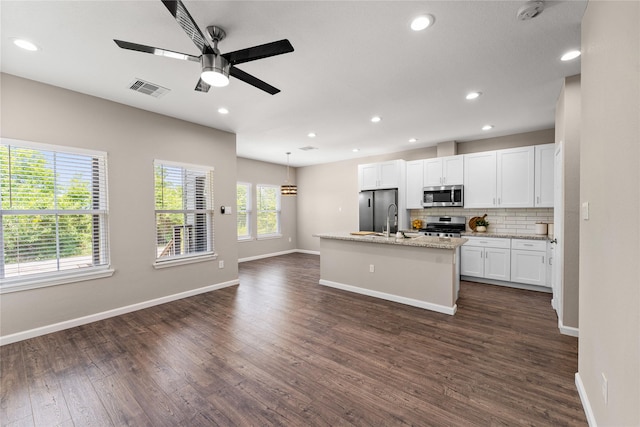 kitchen with white cabinets, dark hardwood / wood-style flooring, a kitchen island with sink, and appliances with stainless steel finishes