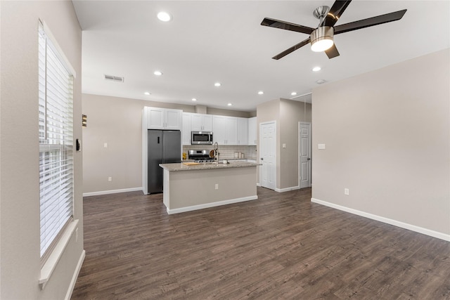 kitchen with light stone countertops, appliances with stainless steel finishes, ceiling fan, dark wood-type flooring, and white cabinetry