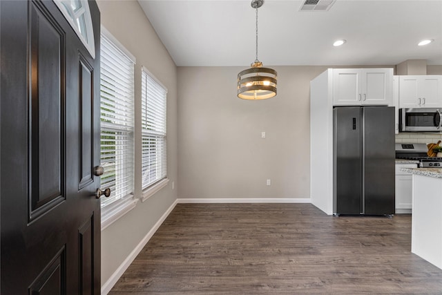 kitchen with hanging light fixtures, appliances with stainless steel finishes, tasteful backsplash, white cabinetry, and a chandelier