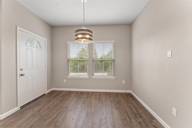 spare room featuring an inviting chandelier and dark wood-type flooring