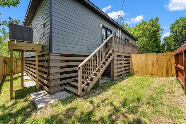 exterior space with a lawn, a deck, and central air condition unit