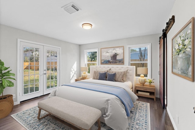 bedroom featuring a barn door, dark wood-type flooring, access to outside, and french doors