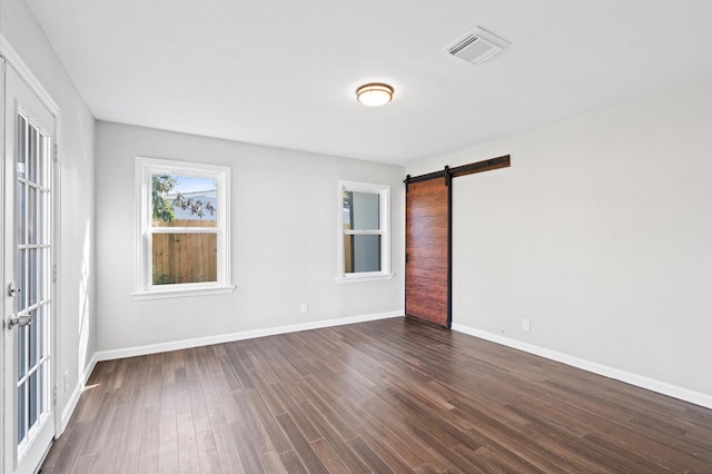 unfurnished room featuring a barn door and dark wood-type flooring