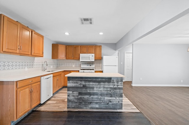 kitchen with hardwood / wood-style floors, white appliances, a center island, and sink