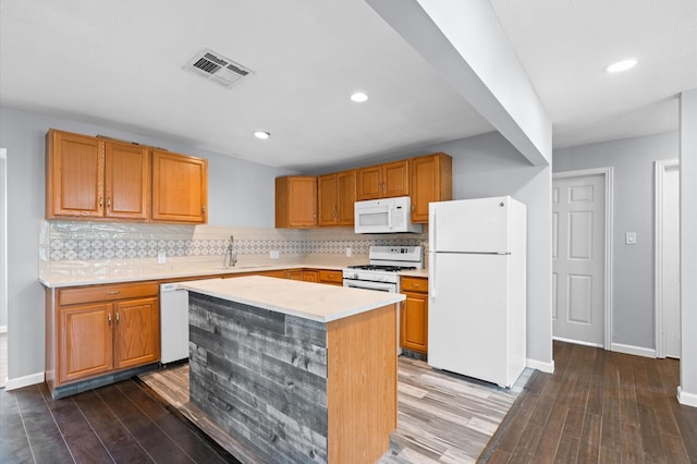 kitchen with white appliances, a center island, dark wood-type flooring, and sink