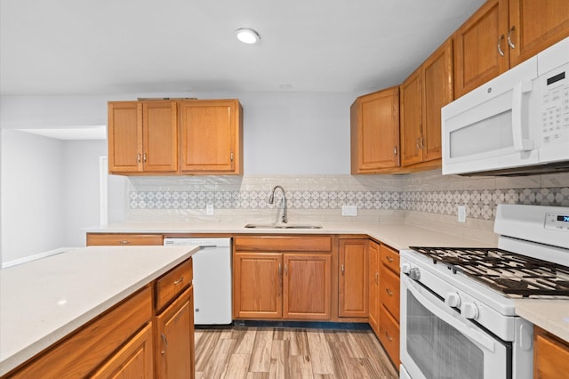 kitchen featuring tasteful backsplash, sink, white appliances, and light wood-type flooring