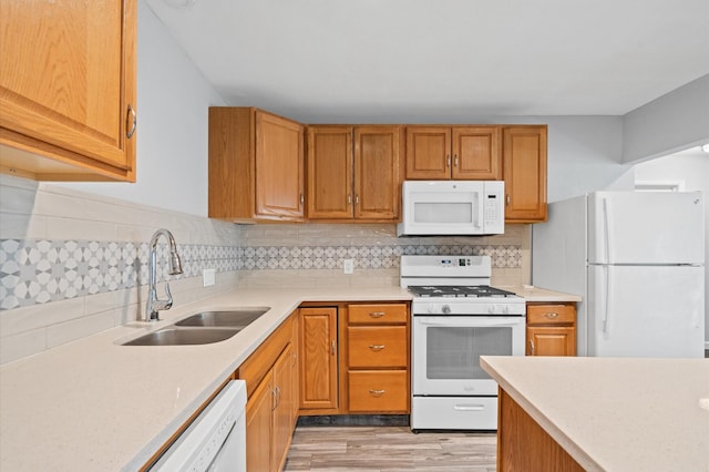 kitchen with decorative backsplash, white appliances, sink, and light hardwood / wood-style flooring