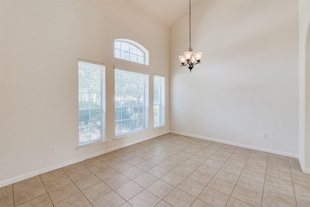 tiled empty room with a healthy amount of sunlight, high vaulted ceiling, and a chandelier