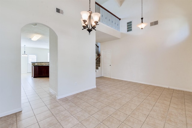 interior space with light tile patterned floors, a towering ceiling, and an inviting chandelier