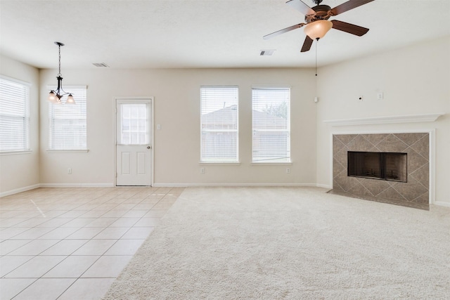 unfurnished living room with a fireplace, light tile patterned flooring, and ceiling fan with notable chandelier