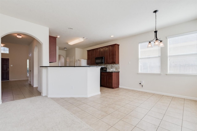 kitchen with a notable chandelier, backsplash, white refrigerator, decorative light fixtures, and light tile patterned floors