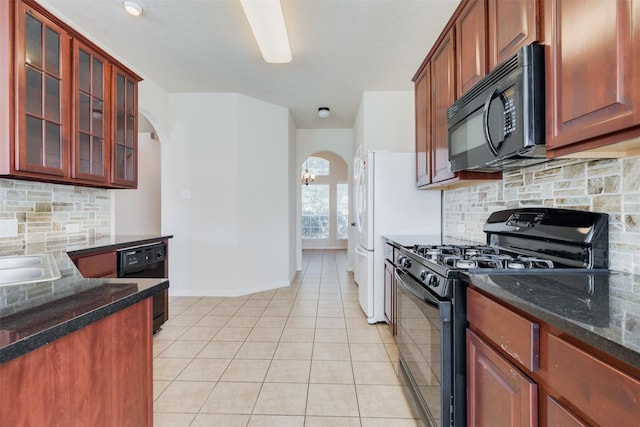 kitchen with dark stone countertops, decorative backsplash, light tile patterned flooring, and black appliances