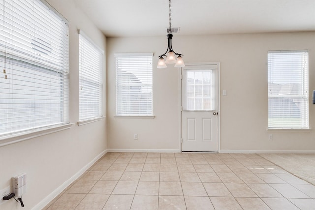 unfurnished dining area featuring a notable chandelier, light tile patterned flooring, and plenty of natural light