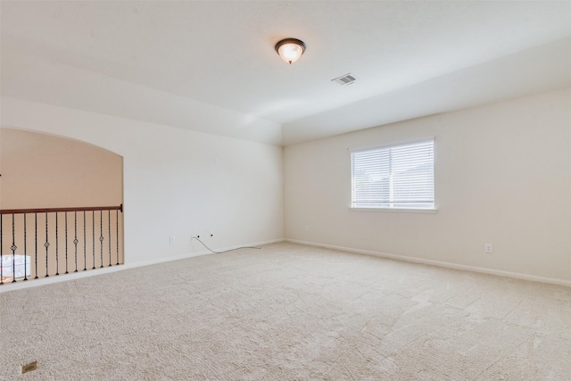 carpeted empty room featuring vaulted ceiling