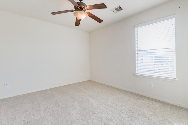 carpeted empty room with ceiling fan and a wealth of natural light