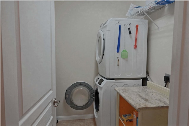 washroom with light tile patterned floors and stacked washer / drying machine