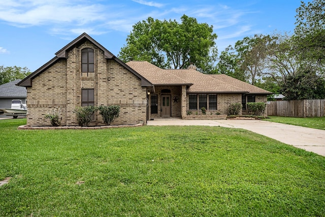 view of front of house featuring fence, a front lawn, and brick siding