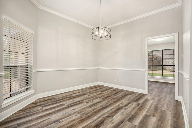 spare room featuring a chandelier, ornamental molding, wood finished floors, and baseboards