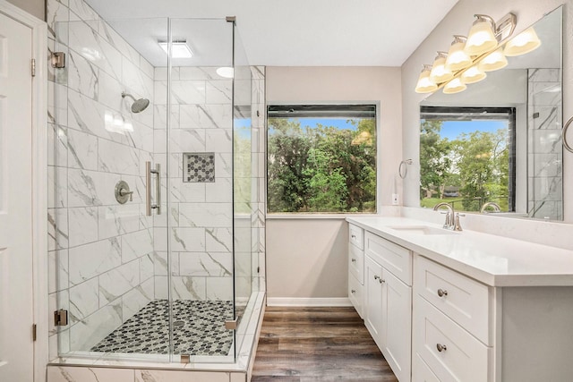 bathroom with a stall shower, plenty of natural light, wood finished floors, and vanity