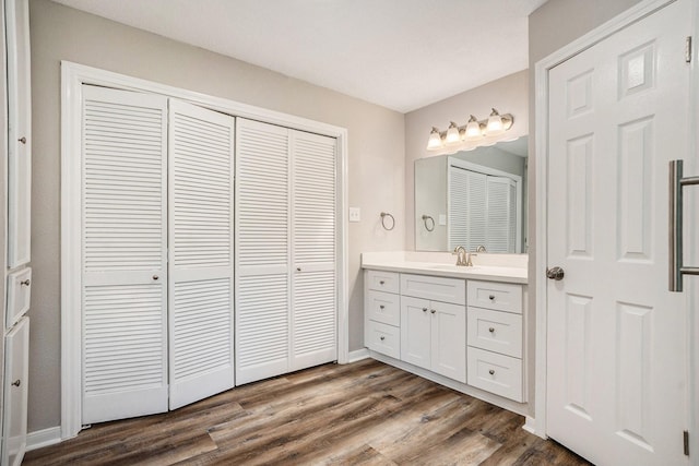 bathroom featuring a closet, wood finished floors, vanity, and baseboards