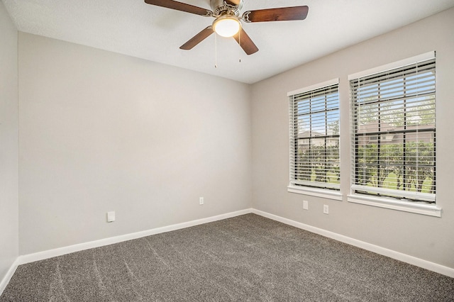 spare room featuring ceiling fan, baseboards, and dark colored carpet