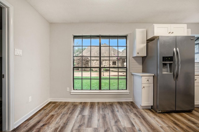 kitchen with wood finished floors, white cabinetry, baseboards, light countertops, and stainless steel fridge with ice dispenser