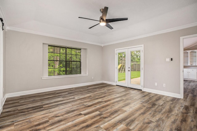 spare room with a barn door, wood finished floors, baseboards, french doors, and crown molding