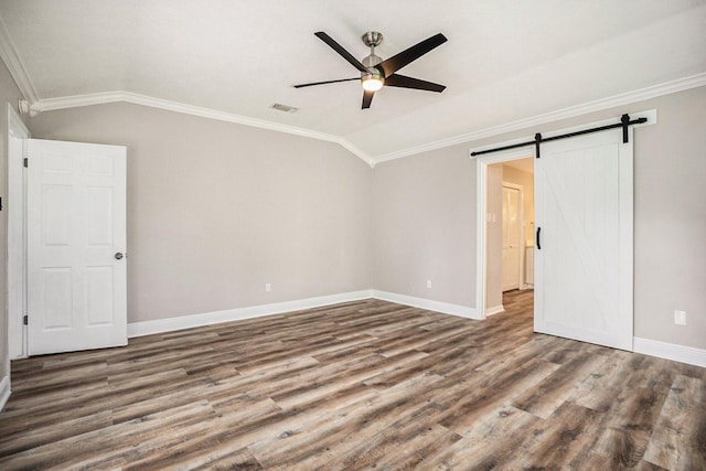 unfurnished bedroom featuring a barn door, visible vents, vaulted ceiling, and wood finished floors