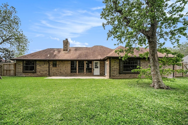 rear view of property featuring brick siding, a yard, a chimney, a patio, and fence