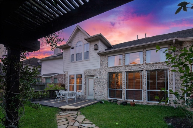 back house at dusk with a lawn and a patio area