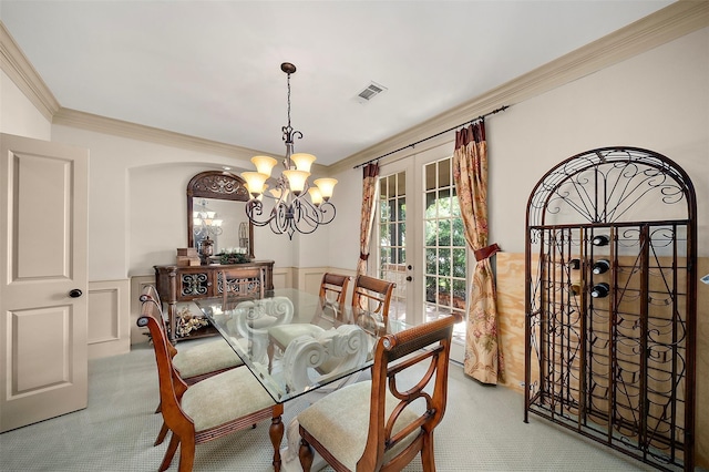 dining area with french doors, light colored carpet, ornamental molding, and an inviting chandelier