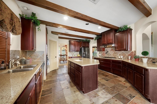 kitchen with a center island, backsplash, sink, appliances with stainless steel finishes, and beam ceiling