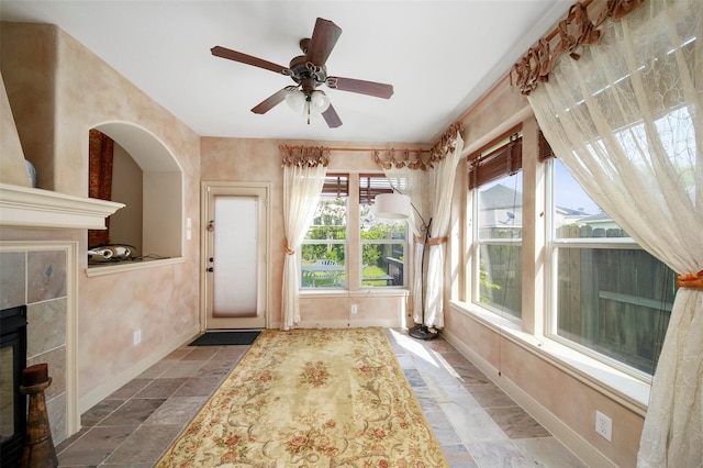 interior space featuring a tile fireplace and ceiling fan