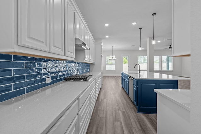 kitchen with blue cabinetry, sink, tasteful backsplash, a center island with sink, and white cabinets