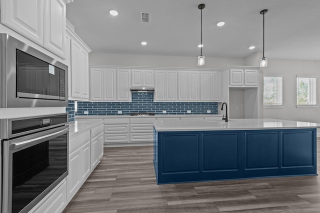 kitchen featuring a center island with sink, decorative light fixtures, white cabinetry, and stainless steel appliances