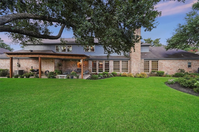 back house at dusk with a lawn and a patio