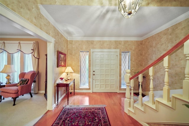 entrance foyer featuring crown molding, hardwood / wood-style flooring, and a notable chandelier