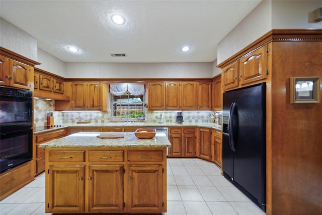 kitchen with decorative backsplash, light tile patterned floors, black appliances, and a kitchen island