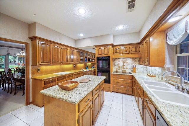 kitchen featuring light tile patterned floors, black double oven, backsplash, sink, and a center island