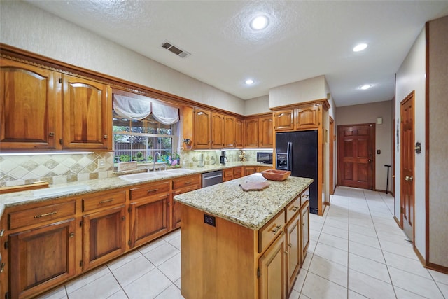 kitchen featuring backsplash, a kitchen island, black refrigerator with ice dispenser, sink, and light stone countertops