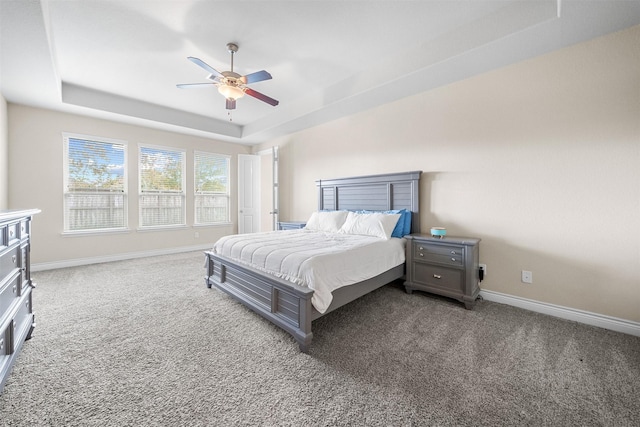 carpeted bedroom with ceiling fan and a raised ceiling