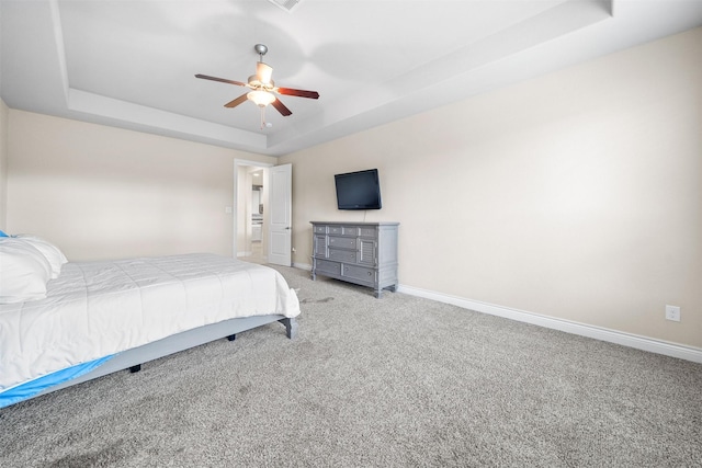 bedroom with a raised ceiling, ceiling fan, and light carpet