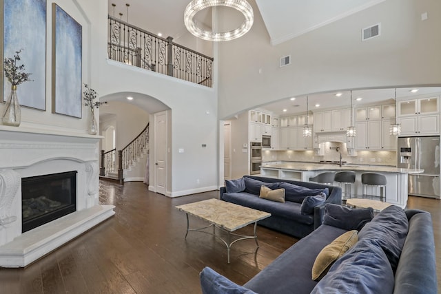 living room featuring sink, dark hardwood / wood-style floors, a high ceiling, and ornamental molding