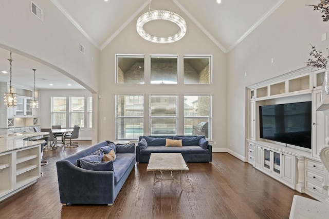 living room with a notable chandelier, dark hardwood / wood-style flooring, crown molding, and high vaulted ceiling