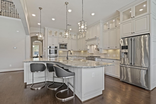 kitchen with decorative light fixtures, white cabinetry, an island with sink, and appliances with stainless steel finishes