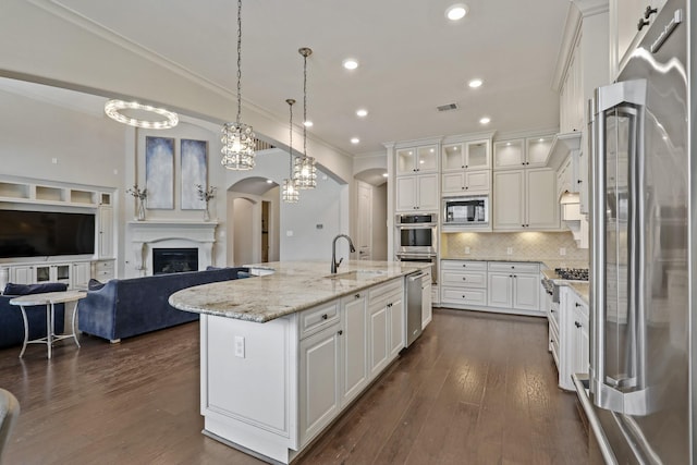 kitchen featuring a kitchen island with sink, sink, decorative backsplash, appliances with stainless steel finishes, and white cabinetry